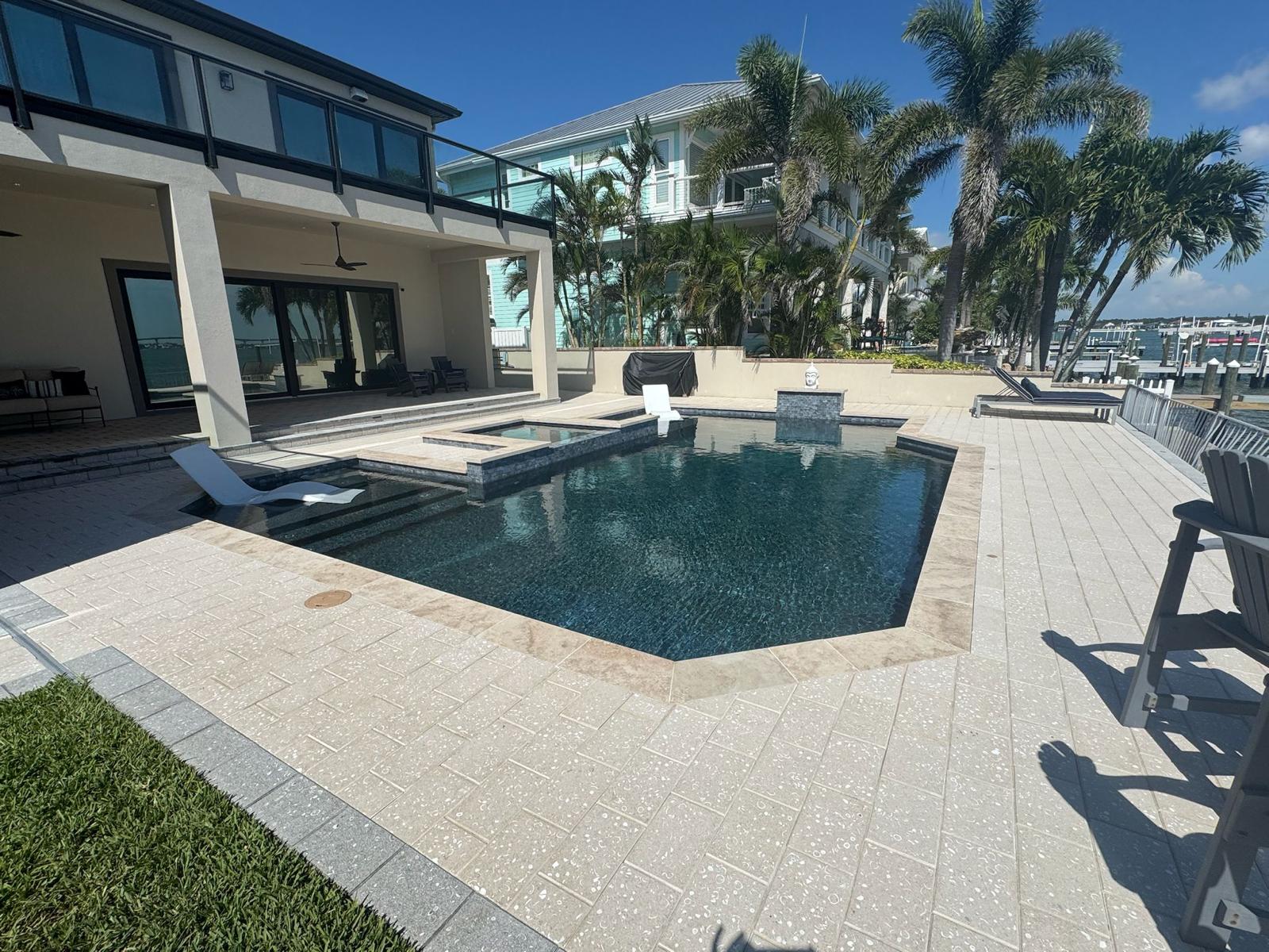 Modern pool beside white home with palm trees in St. Petersburg