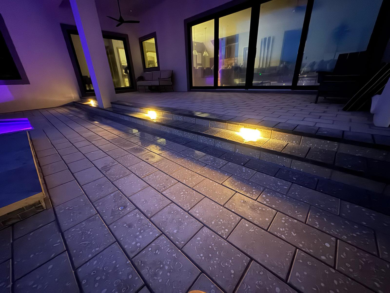 Close-up of lit paver steps leading to custom pool at dusk in Tampa