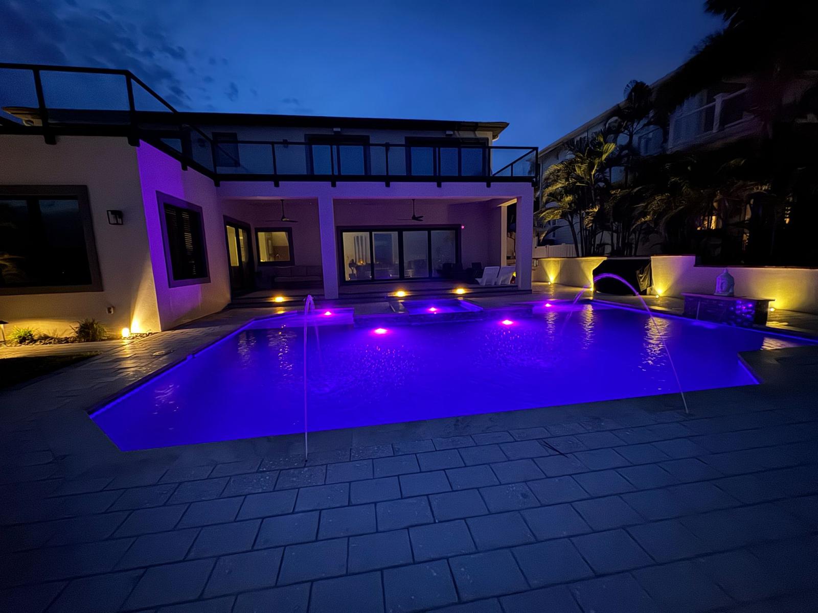 Evening view of glowing purple pool lights in a Clearwater backyard