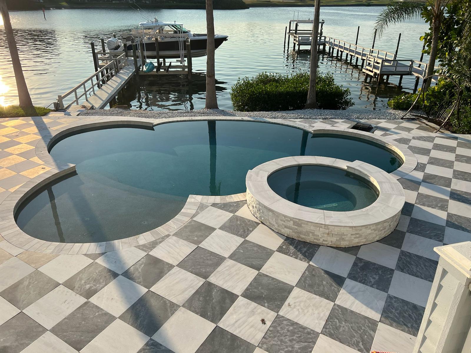 Round spa with water view and black-and-white checkered pool deck in Tampa