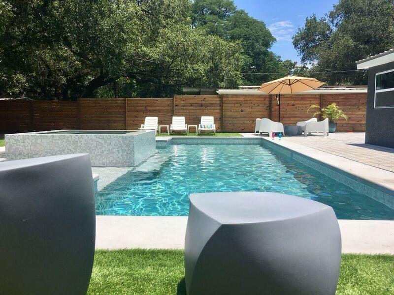 Backyard pool with turf seating and fire pit in a Tampa outdoor living space