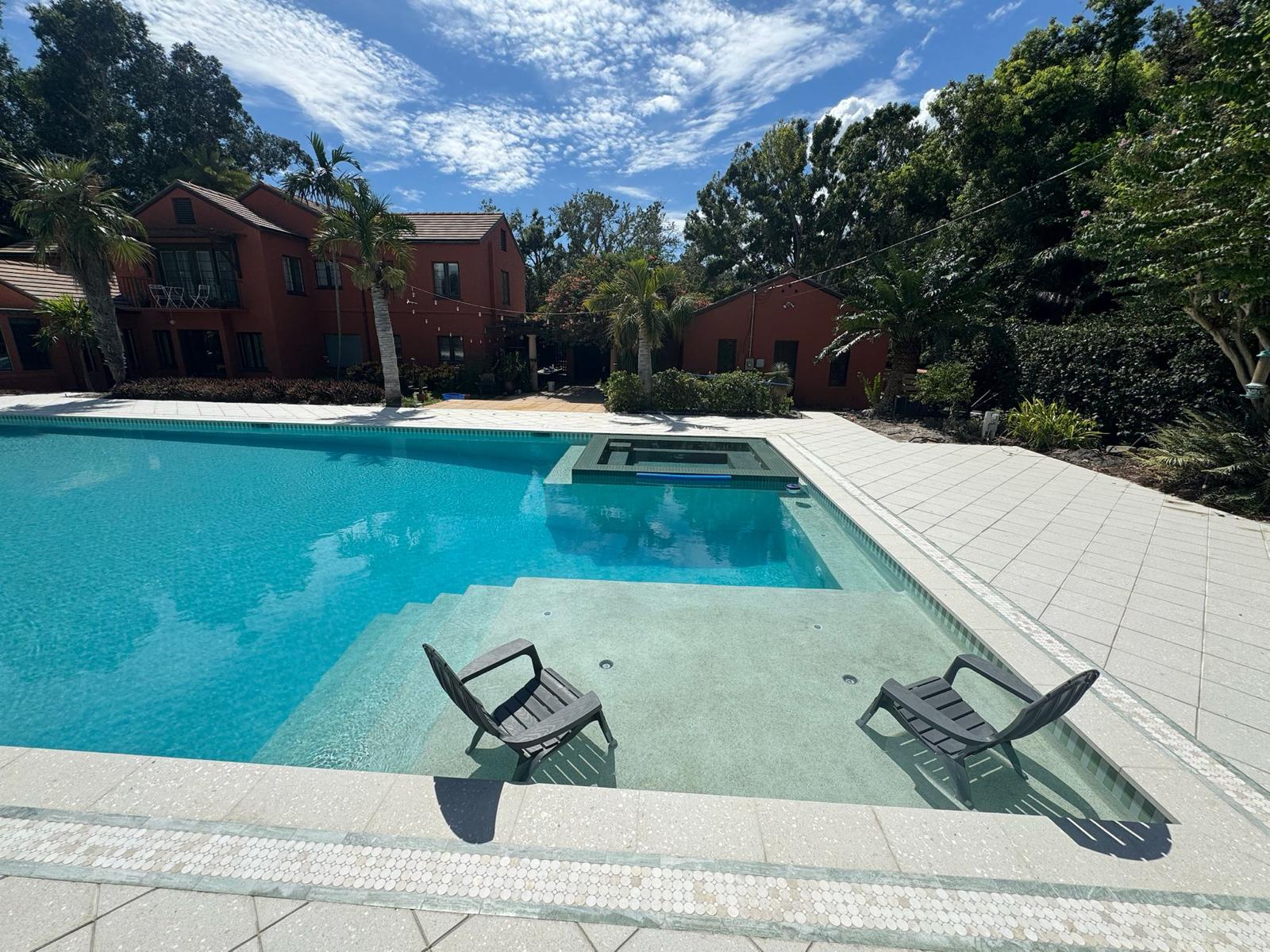 Pool with tanning ledge and two chairs in a tropical Clearwater backyard
